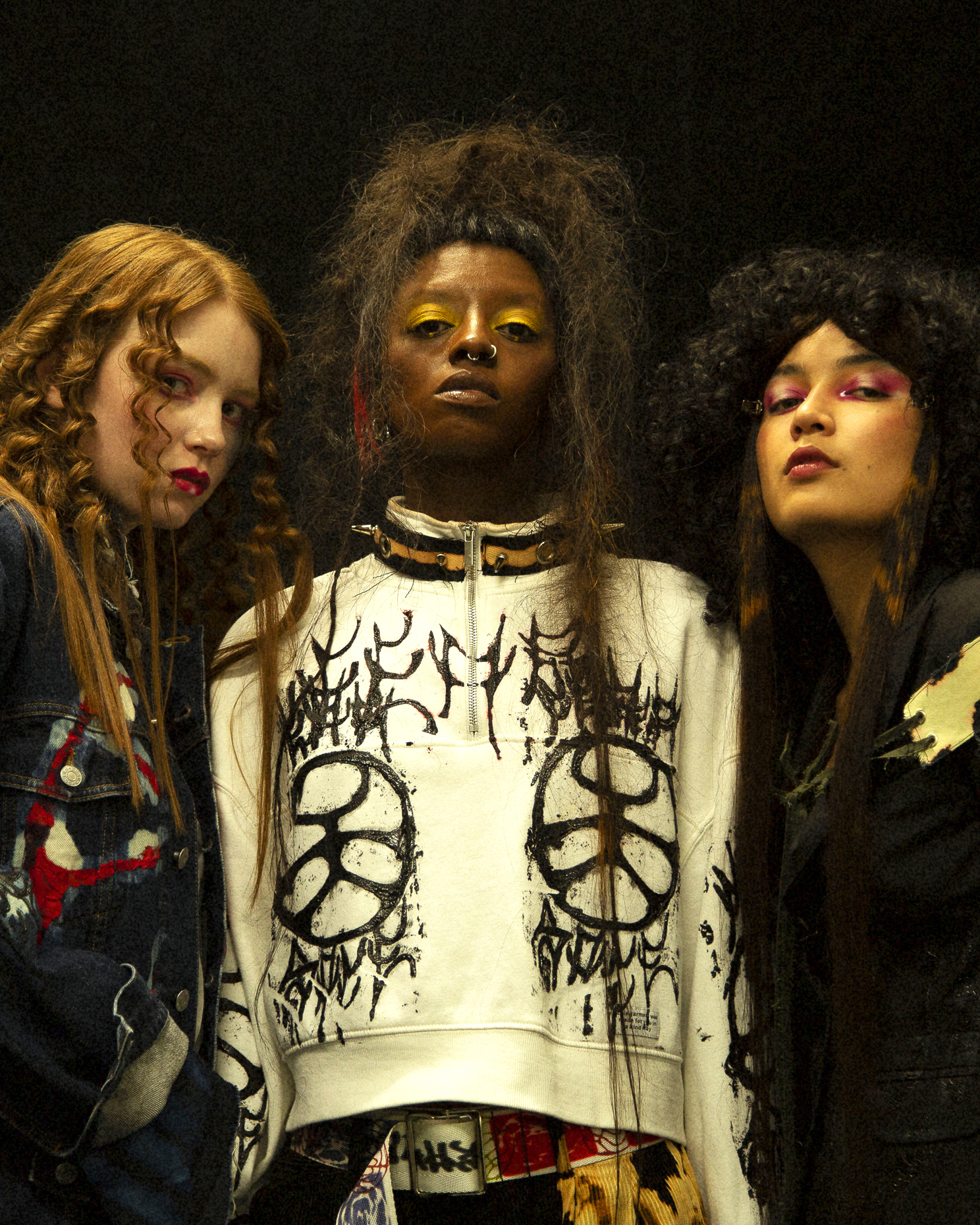 Glamor shot of three models on a black background with colorful eye makeup on
